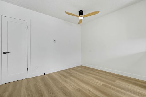A room with a ceiling fan and wooden flooring.
