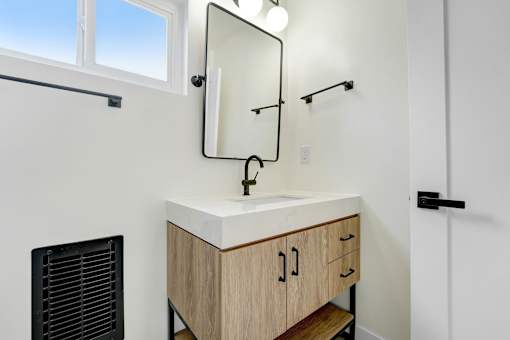A bathroom with a sink, mirror, and cabinets.