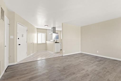 A spacious room with light wood flooring and white walls.