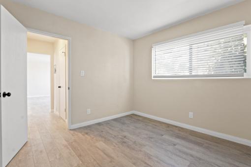 A room with a white door and a window with blinds.