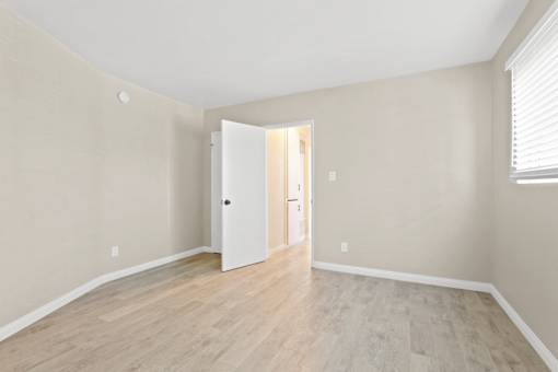 A room with a white door and wooden floor.