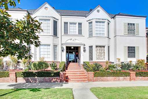 A white two-story house with a red brick staircase leading to the front door.