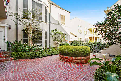 A red brick pathway leads to a white building with a black door.