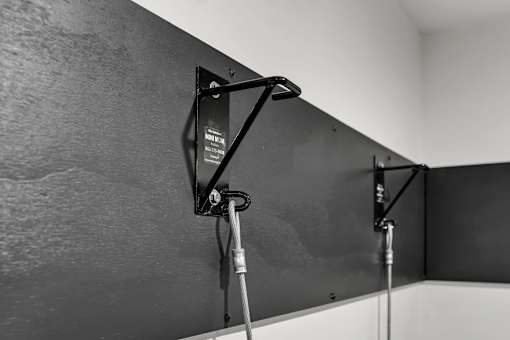 A black and white photo of a wall-mounted monitor with a cable attached to it.