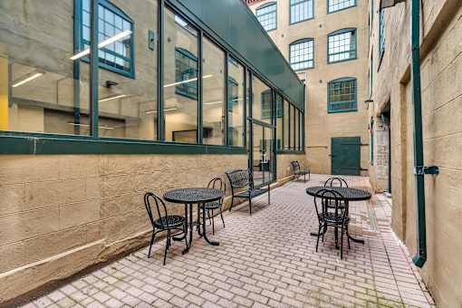 A patio with tables and chairs is surrounded by a wall.