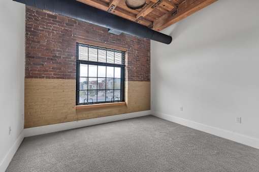 A room with a brick wall and a window.