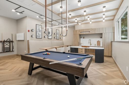A pool table is in the middle of a room with a wooden floor.