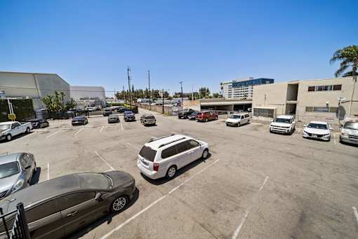 A parking lot with several cars and a building in the background.