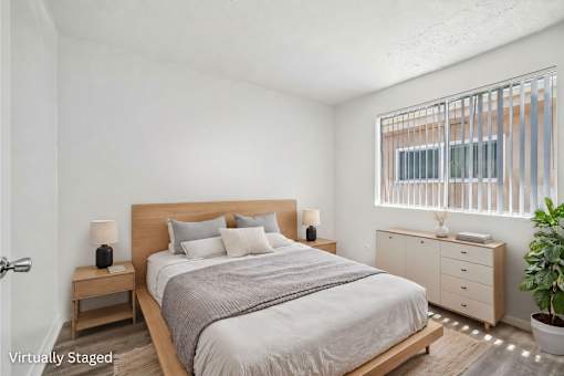 A bedroom with a bed, nightstands, and a plant.