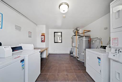 A laundry room with washing machines and a bench.