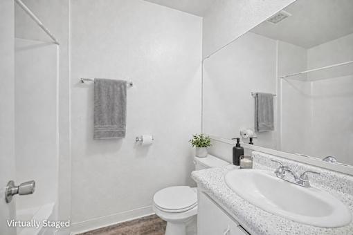 A white bathroom with a toilet, sink, and mirror.