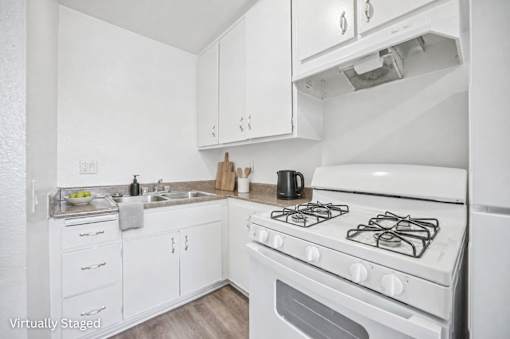 A white kitchen with a stove top oven and a sink.