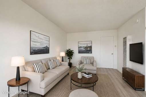 A living room with a white couch, a coffee table, and a television.