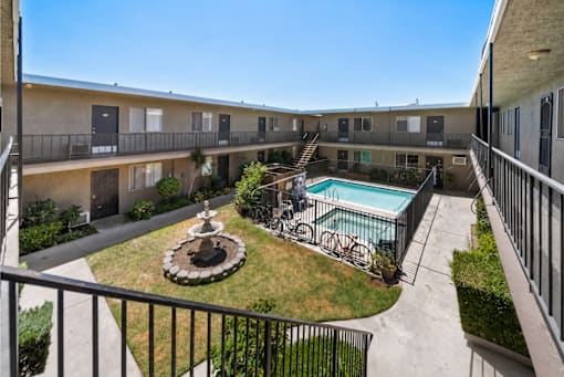 A balcony overlooks a courtyard with a fountain and pool.