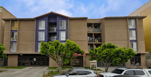 A large apartment complex with a parking lot in front.