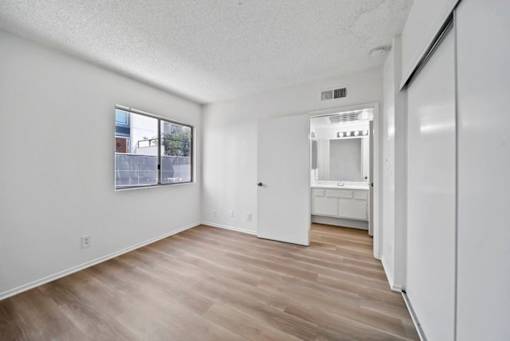 A white room with a wooden floor and a window.