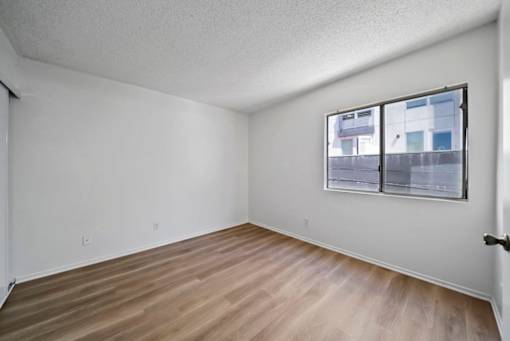 Empty room with a window and wooden flooring.