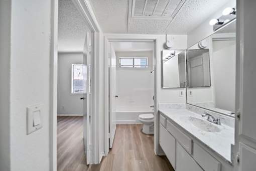 A white bathroom with a toilet, sink, and mirror.