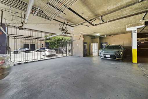A car is parked in a garage with a yellow pole to the right.