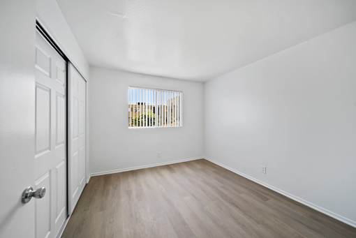 A room with a white door and a window with blinds.