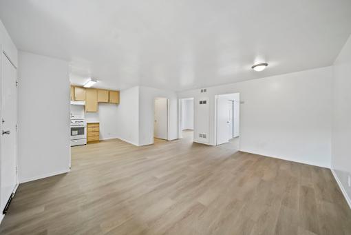 A spacious room with wooden flooring and white walls.