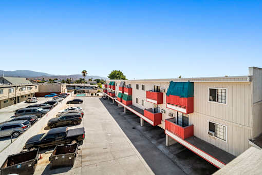 A parking lot with cars and a building with red and green stripes.