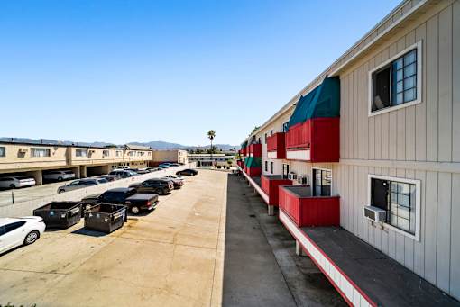 A parking lot with cars and a building with red and green awnings.