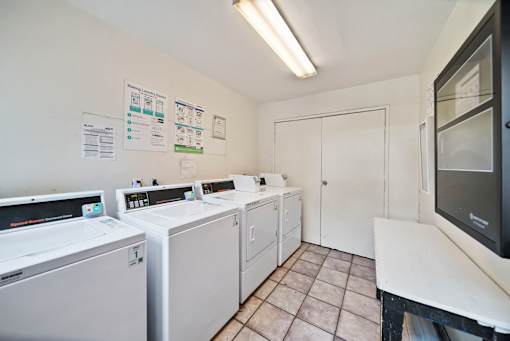 A laundry room with washers and dryers and a white door.