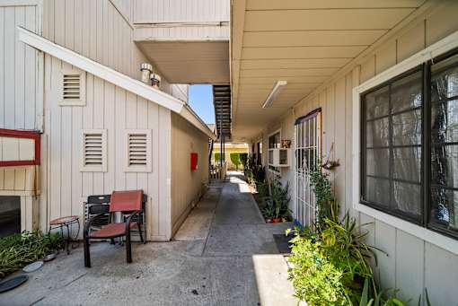 A long, narrow walkway between two buildings with benches on the left side.