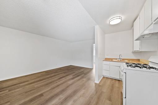 A kitchen with a white stove and wooden floors.