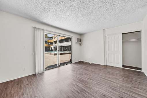 A room with a sliding glass door and wood flooring.