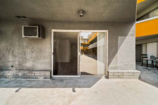 A concrete building with a glass door and a small window on the wall.