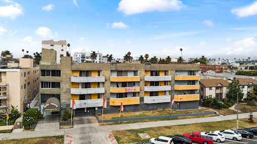 A parking lot with cars and a multi-story building in the background.