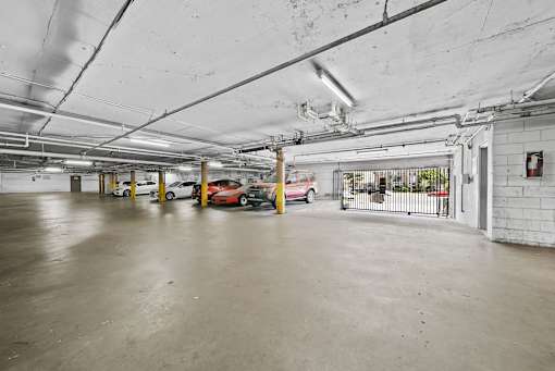 A parking garage with a few cars and a fire extinguisher on the wall.