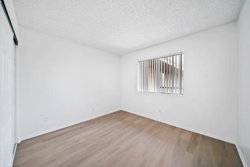 A room with a wooden floor and a window with bars on it.