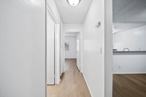 A long hallway with white walls and wood floors.