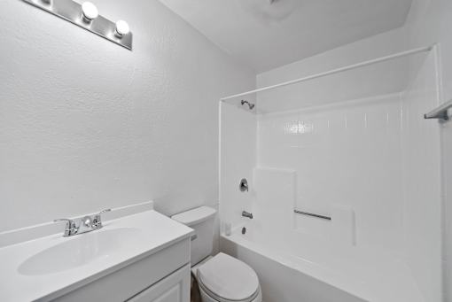 A white bathroom with a toilet, sink, and shower.