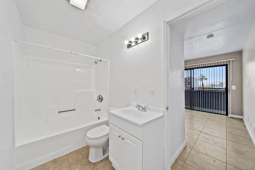 A white bathroom with a toilet, sink, and shower.
