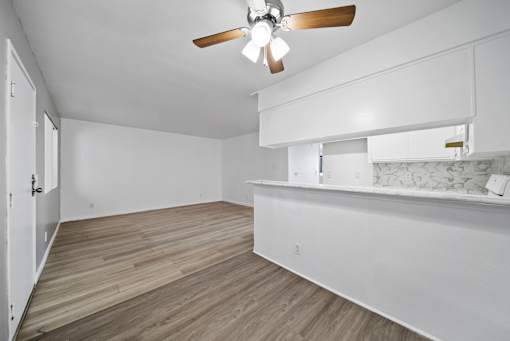 A room with a ceiling fan and wooden flooring.