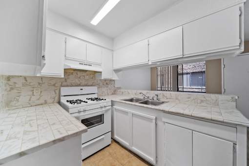 A kitchen with white cabinets and a marble countertop.
