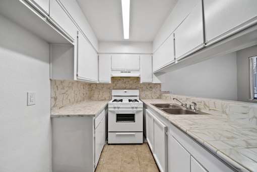 A kitchen with white cabinets and a marble countertop.
