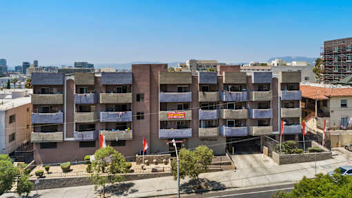 A large apartment complex with a red sign in front.