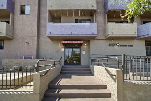 The image shows the front of a building with a red sign that reads "Sunrise Towers Apartments."