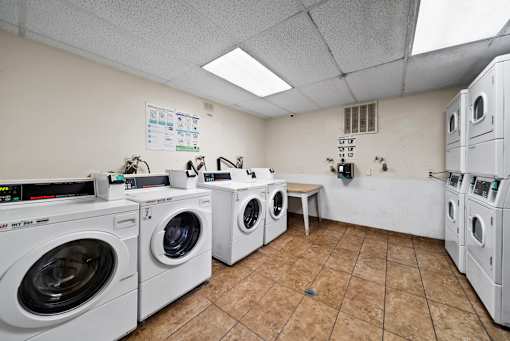 A laundromat with several washing machines and a white wall.