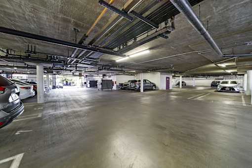 A parking garage with cars parked on the ground floor.