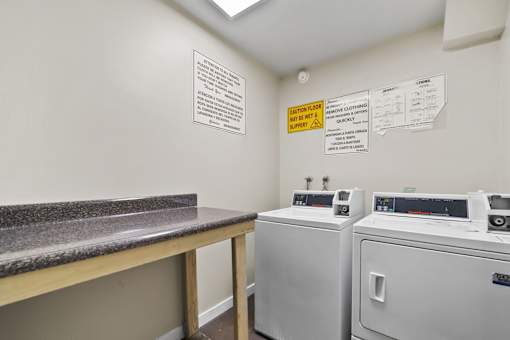 A laundry room with washers and dryers and a counter.