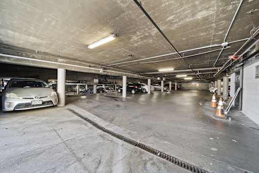 A parking garage with a car parked and a few orange cones.