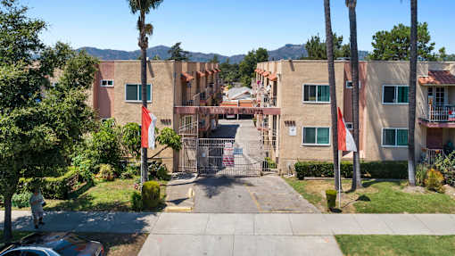 A gated entrance to a residential complex with a flag on a pole.