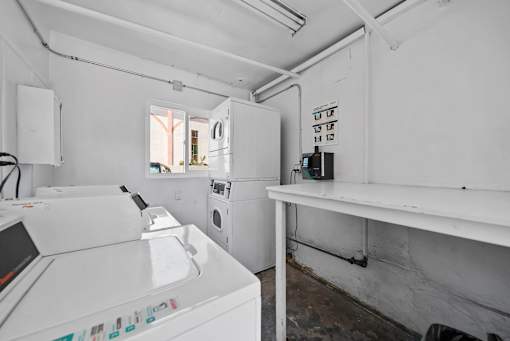 A white washing machine is in a room with a white wall.