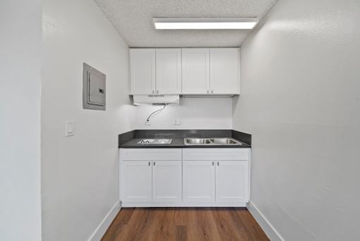 A kitchen with white cabinets and a black countertop.